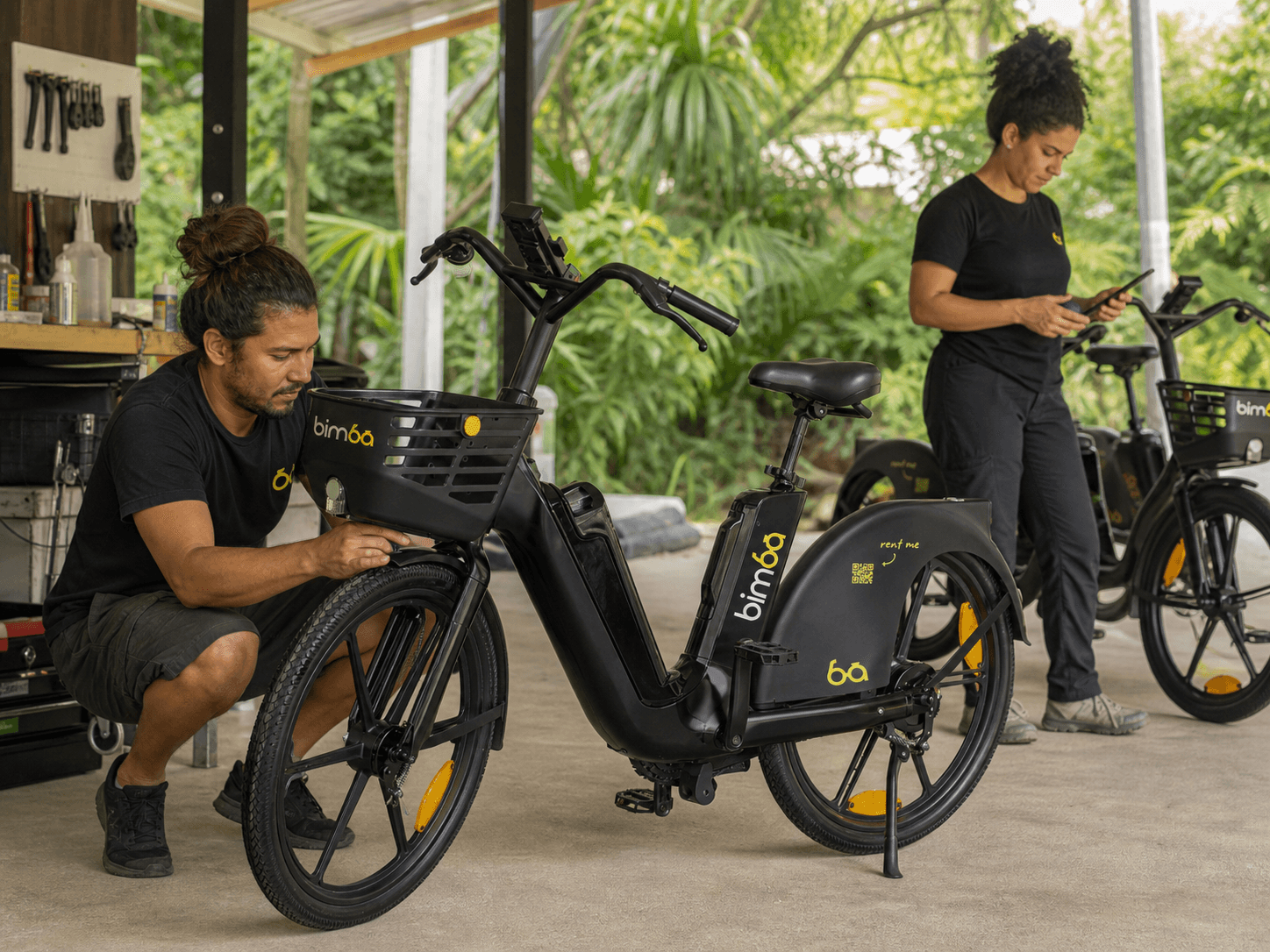 Two local Bimba team members inspecting electric bikes and preparing the fleet for riders