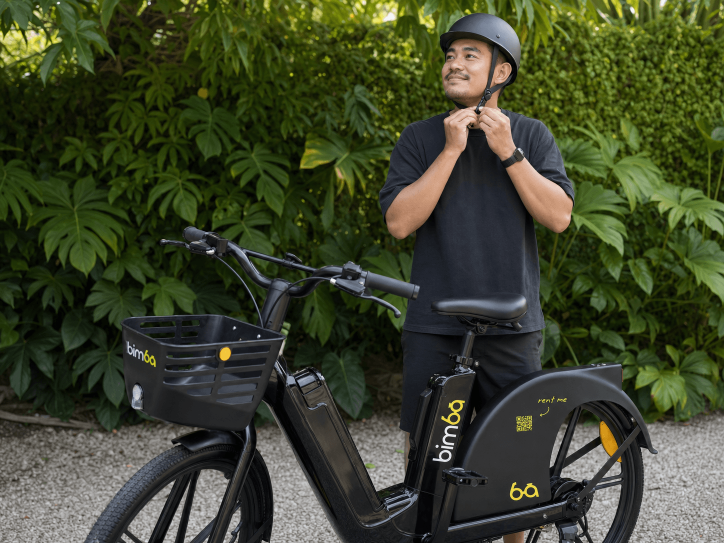 Bimba rider fastening a properly fitted helmet beside a stationary e-bike