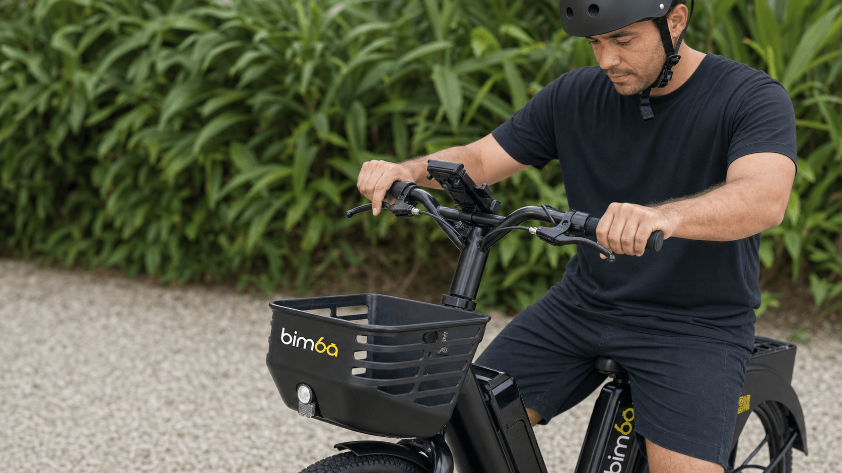 Helmeted rider checking both brake levers on a stationary black Bimba e-bike