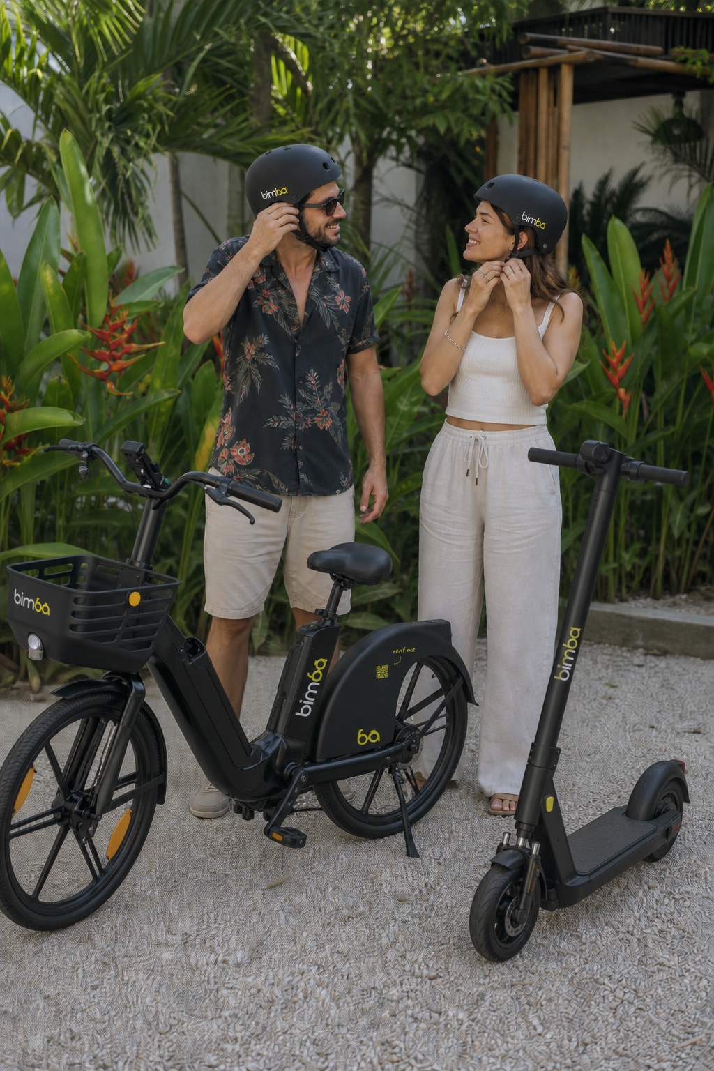Un hombre y una mujer se ponen cascos Bimba junto a una bicicleta eléctrica y un scooter OKAI ES400A en Santa Teresa