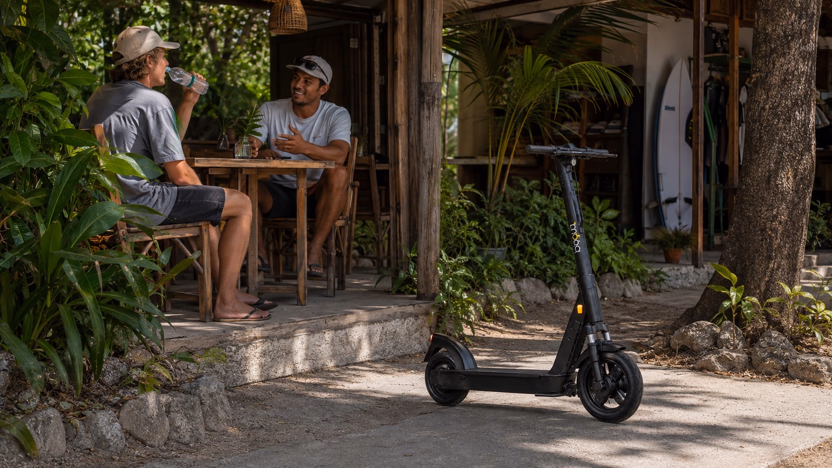 Beginner surfer recovering at a Playa Carmen café with an exact-model Bimba scooter parked outside