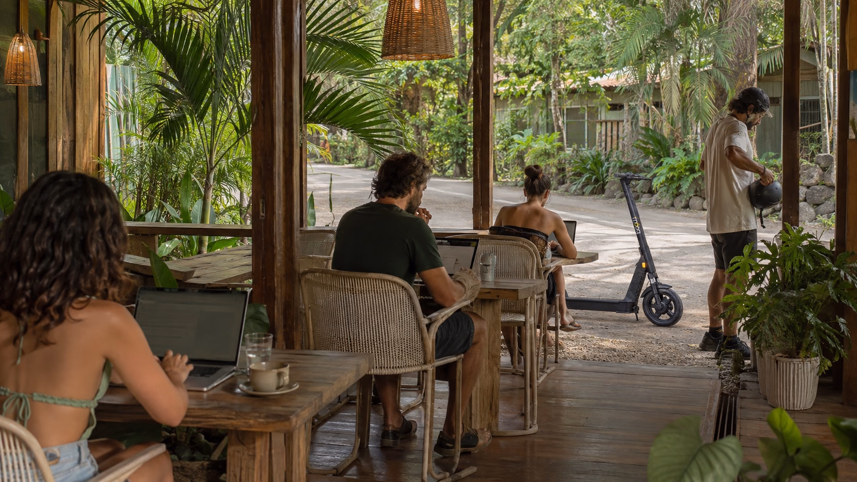 Remote workers in an open-air Santa Teresa café with an exact-model Bimba scooter outside