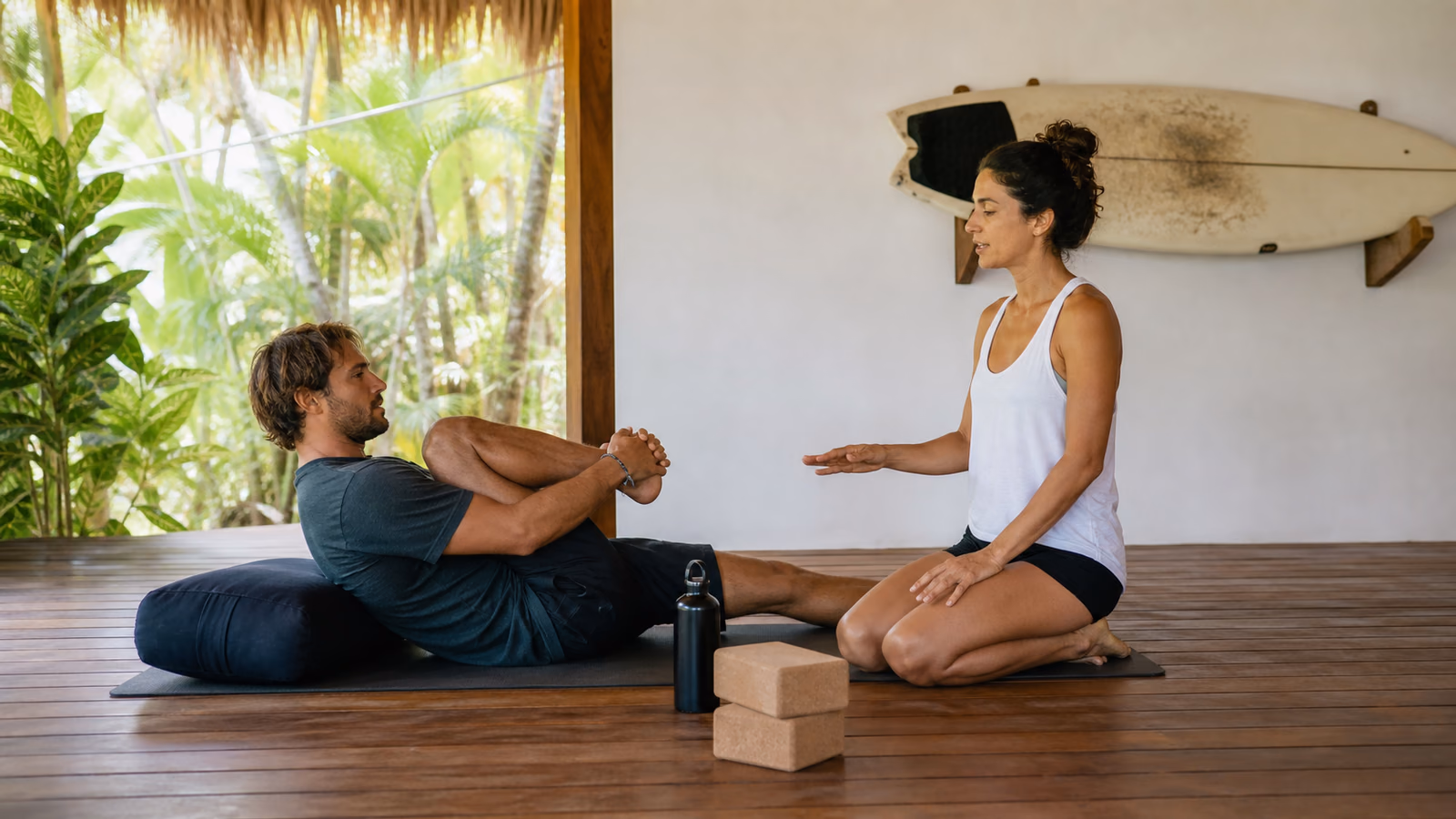 Surfer practicing a gentle supported recovery stretch with guidance from a yoga teacher