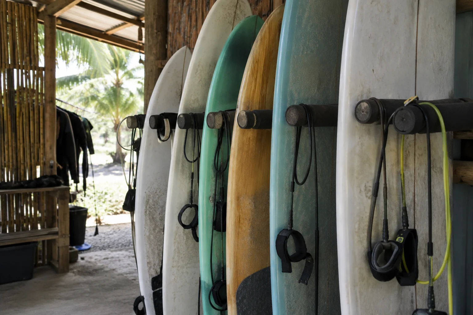 Tablas de surf y leashes organizados en un soporte de alquiler